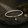 String of shell pearls with a square zircon charm on mossed slate