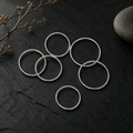 Six fine polished silver open bands stacked on slate