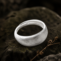 Wide brushed matte silver band on slate in raking light