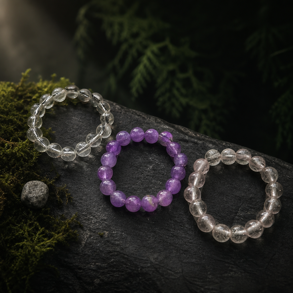 Clear, pale grey and soft pink crystal bead rings on mossed stone